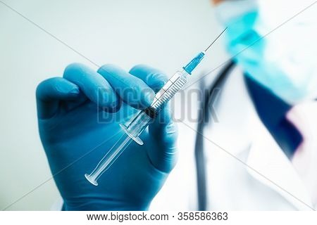 Close Up Hand Of Doctor In Blue Latex Glove And Medical Gauze Mask With Transparent Syringe. Health 