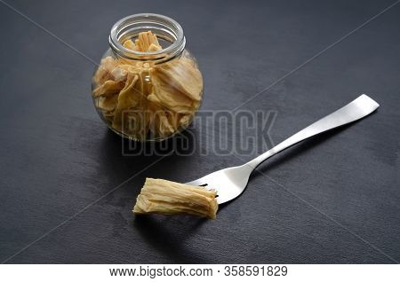 Fermented Soy Tofu Yuba Leather With In A Jar And On A Fork On A Black Slate Background. East Asian 