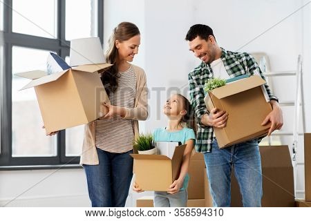 mortgage, family and real estate concept - happy mother, father and little daughter with stuff in boxes moving to new home