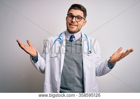 Young doctor man with blue eyes wearing medical coat and stethoscope over isolated background smiling showing both hands open palms, presenting and advertising comparison and balance