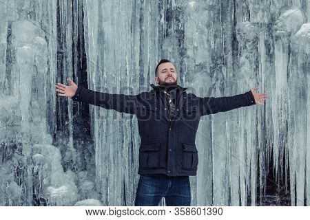 Man standing against cliff full of icicles