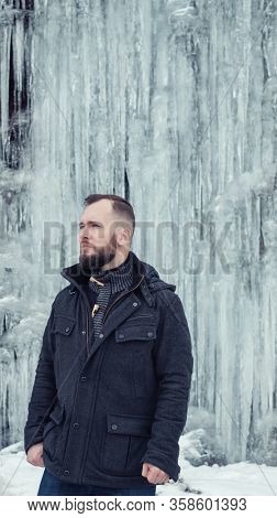 Man standing against cliff full of icicles