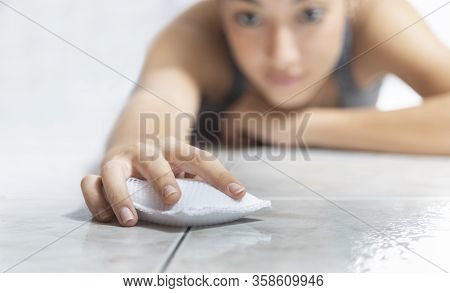 Woman Lying Down Wiping The Floor With A Sponge To Disinfect It