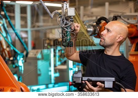 Engineer Doing Maintenance For Automatic Robot Arms In Smart Automotive Factory, Industrial Concept