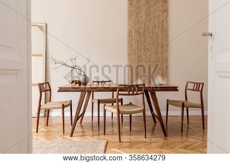 Stylish And Beige Interior Of Dining Room With Design Wooden Table And Chairs, Raw Tree Branch In Va
