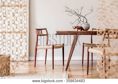Stylish And Beige Interior Of Dining Room With Design Wooden Table And Chairs, Raw Tree Branch In Va