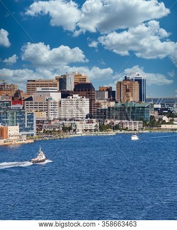 A Tugboat Sailing Past The City Of Halifax, Nova Scotia In Blue Water