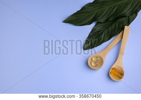 Healthy Supplements On Wooden Teaspoons With Green Leafs On Blue Background
