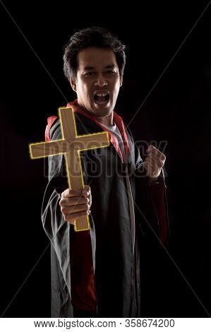 Dark Tone, Rim Light - Priest Show Lighting Crucifix While Holding Bible To Exorcise Ghost On Black 