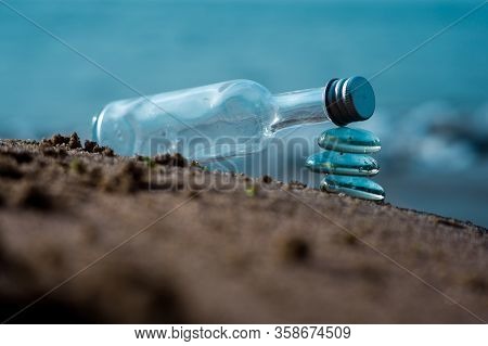 Colorgraded Transparent Bottle On Stack Of Glass Stones Symbolizing Balance