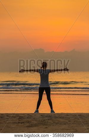 Good Shape Woman Standing And Exercise On Beanch In The Morning With Colorful Sky In Background.