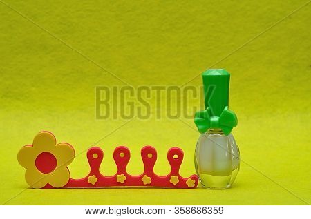 A Bottle Of White Nail Polish With A Toe Separator