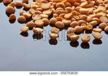 A Small Amount Of Pea Groats Poured Onto A Black Reflective Surface, Background. Legumes. Fabales