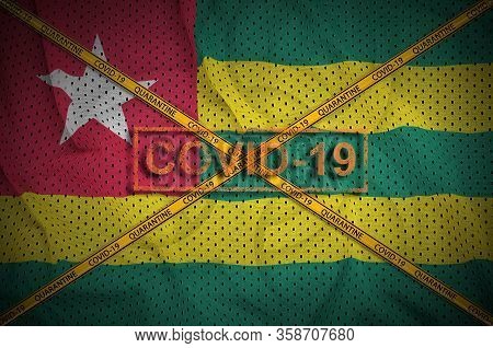 Togo Flag And Covid-19 Stamp With Orange Quarantine Border Tape Cross. Coronavirus Or 2019-ncov Viru