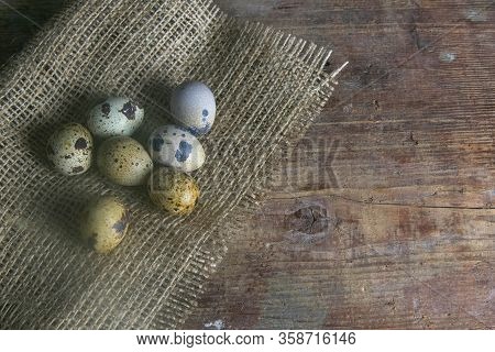 The Quail Eggs Stand On The Burlap On The Wooden Table Next To A Flowerin. Top Views With Clear Spac