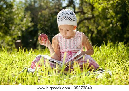 かわいい女の子は、子供向けの本を読んでいます。