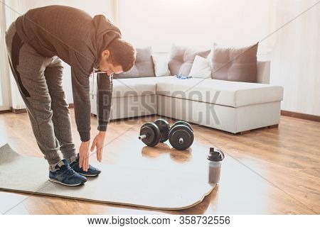 Young Ordinary Man Go In For Sport At Home. Stand On Mat And Stretch Down To Toes. Ordinary Guy Warm
