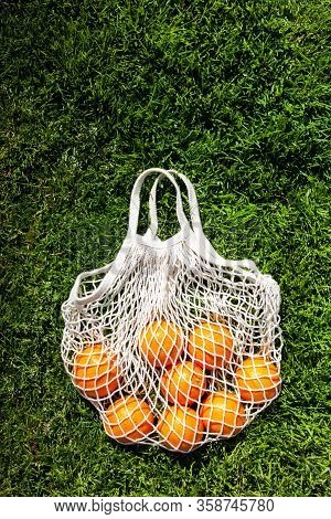 White Cotton Eco String Bag With Oranges On A Grass. Good Idea For A Picnic. Zero And Eco Waste. No 