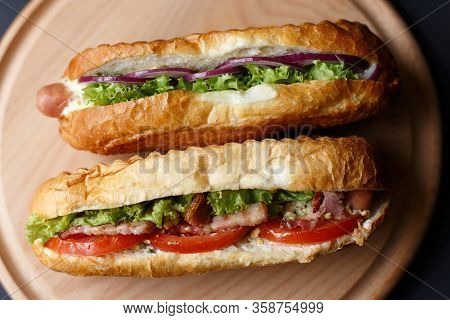 Two Hot Dogs Lying On The Wooden Plate.