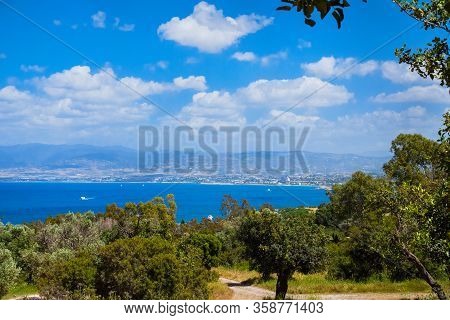 Summer Seascape On Cypus. View To The Bay With Green Grove In Front And Blue Clouded Sky. View From 