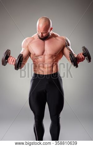 Sexy Muscular Bodybuider Posing With Weights On The Gray Background