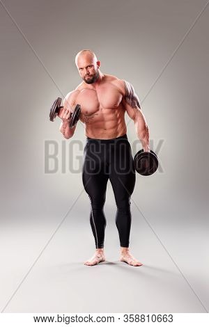 Sexy Muscular Bodybuider Posing With Weights On The Gray Background