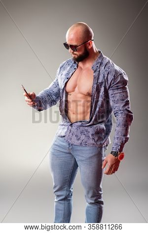 Sexy Unbuttoned Muscular Bodybuider With Sunglasses On The Gray Background. Selfie Concept