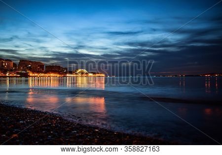 cloudy evening view of the bright lights of the building and the city center of the resort of Gelendzhik from the beach. Black sea coast