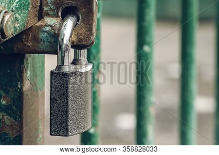 Closed And Locked Door Grill With Silver Padlock. A Metal Lock On Hinges Hangs In Close-up On The Gr