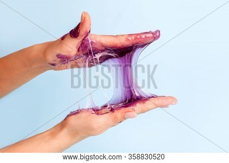 Young Girl Hands With Sticky Purple Slime On Blue Background, Liqiud Wax For Depilation, Conceptual 