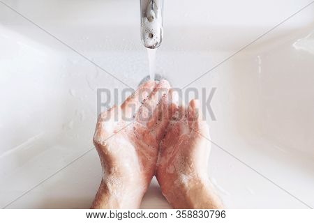 Man Cleaning His Hands Using Liquid Disinfectant Soap And Water In Bathroom.