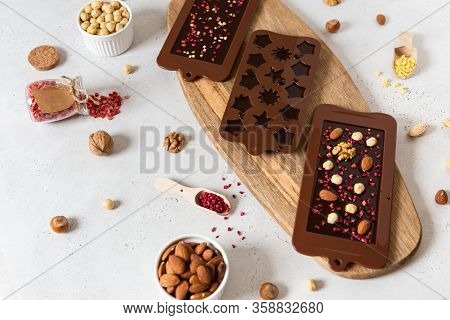 Raw Vegan Handmade Chocolate With Nuts And Dried Fruits In Molds. Chocolate Bars And Pralines On Whi