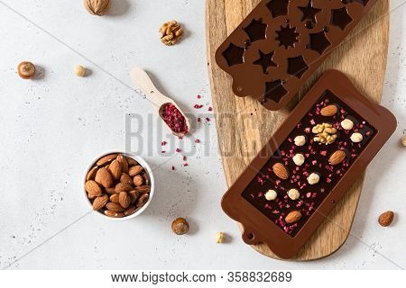 Handmade Dark Chocolate Bar And Candies In Molds With Nuts And Dried Fruits On White Background. Top