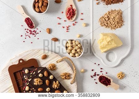 Homemade Dark Chocolate Bars And Pralines In Molds With Dried Berries And Nuts On White Background. 