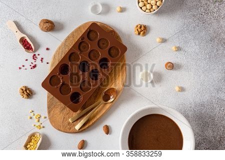 Raw Vegan Handmade Chocolate Candies In Mold With Nuts And Dried Fruits On White Concrete Background