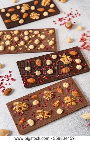 Variety Of Chocolate Bars, Nuts And Ingredients On White Wooden Background. Handmade Organic Chocola