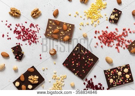 Variety Of Chocolate Bars, Nuts And Ingredients On White Wooden Background. Handmade Organic Chocola