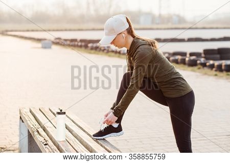 Beautiful Girl At Morning Workout Outdoors In Black Leggings And With A Bottle Of Water