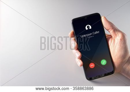Male Hand Holding A Smartphone With Unknown Caller Displayed On Screen. Privacy, Fraud, Cybercrime A