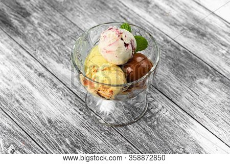 Colored Balls Of Ice Cream In A Glass Cremant On Wooden Grey Background.