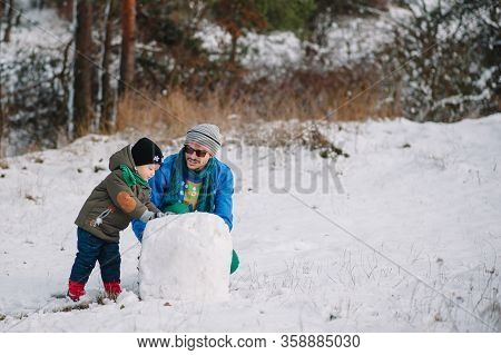 Father And Little Toddler Boy Walking In The Winter Forest And Having Fun With Snow. Family Enjoying