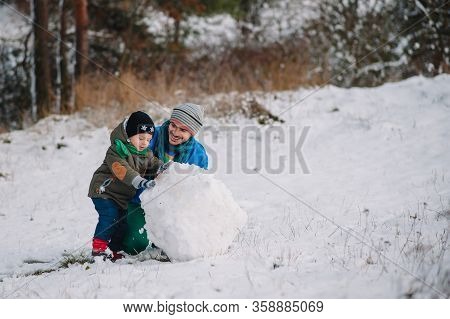 Father And Little Toddler Boy Walking In The Winter Forest And Having Fun With Snow. Family Enjoying