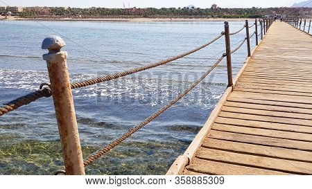 Long Pontoon On The Red Sea In Egypt. Pontoon For Descent Into The Water. Wooden Bridge On The Terri