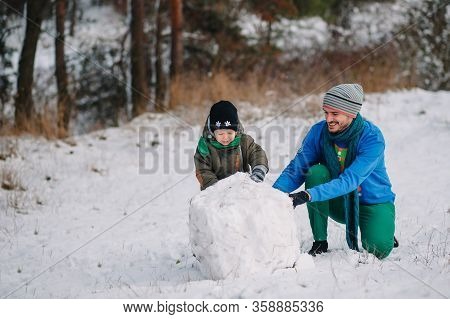 Father And Little Toddler Boy Walking In The Winter Forest And Having Fun With Snow. Family Enjoying