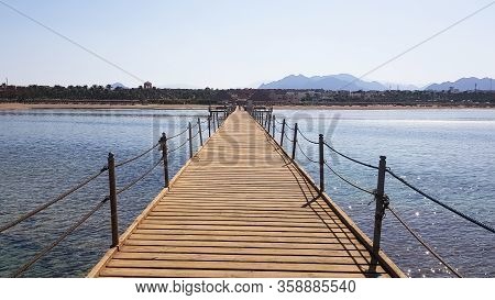 Long Pontoon On The Red Sea In Egypt. Pontoon For Descent Into The Water. Wooden Bridge On The Terri