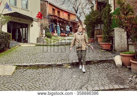 A Young Caucasian Woman On A Tour Of Istanbul Goes Down A Deserted Street. A White Female, Dressed I