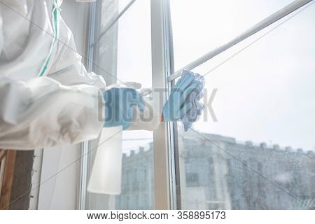 Coronavirus Pandemic. A Disinfector In A Protective Suit And Mask Sprays Disinfectants In House Or O
