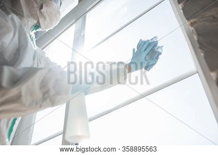 Coronavirus Pandemic. A Disinfector In A Protective Suit And Mask Sprays Disinfectants In House Or O