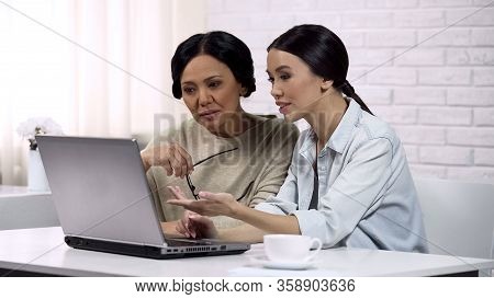 Young Woman Teaching Grandma To Use Computer App, Writing Email, Generation Gap