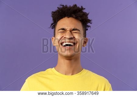 Close-up Portrait Of Happy Carefree Young Guy Laughing Loud, Chuckling Over Hilarious Joke, Bending 